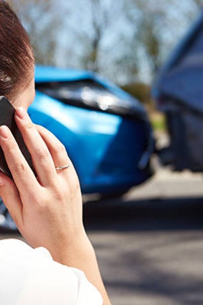 Female Driver Making Phone Call After Traffic Accident, looking at the accident